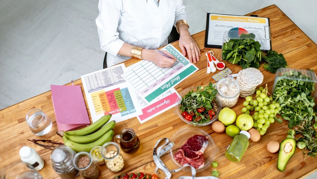 A practitioner reviewing lab results beside fresh fruit, vegetables, and supplements